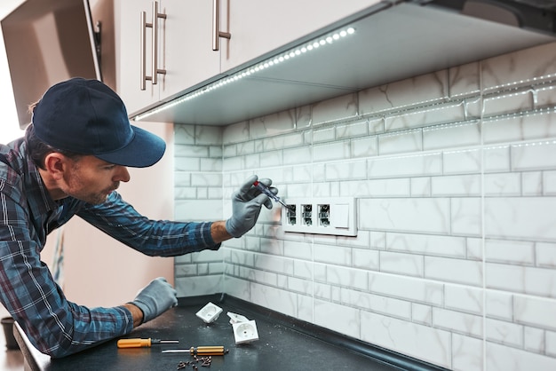 Alles ist eine sichere Seitenansicht des jungen Handwerkers, der neue Steckdosen setzt