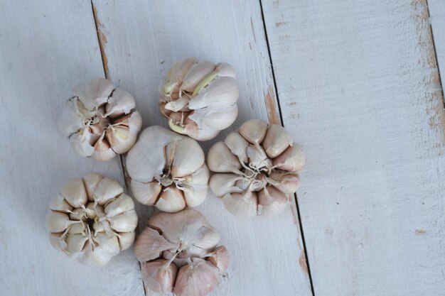 Allium sativum. pedaço inteiro de alho em uma mesa de madeira branca. O alho é um tempero de cozinha.