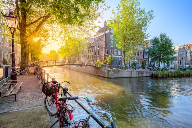 Alma de Amsterdã Madrugada em Amsterdã Casas antigas uma ponte bicicletas tradicionais canais e o sol brilha por entre as árvores Ótimo dia em Amsterdã