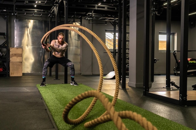 Almacén de cuerdas fitness hombre verde hierba entrenamiento gimnasio musculoso joven para una fuerte fuerza física