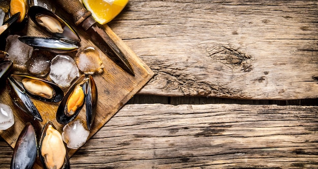 Almejas con limón y hielo sobre una tabla de madera.