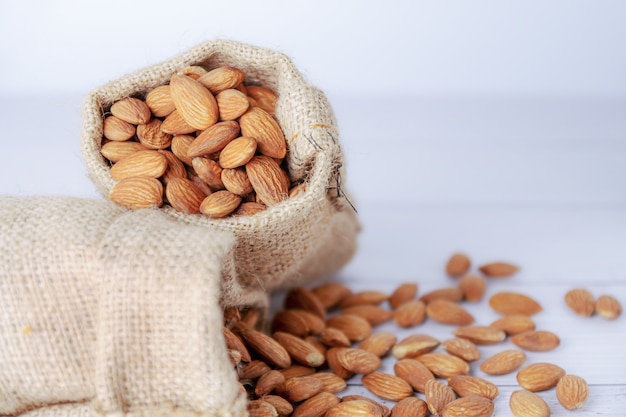 Almendra en bolsa de tela en mesa blanca borrosa