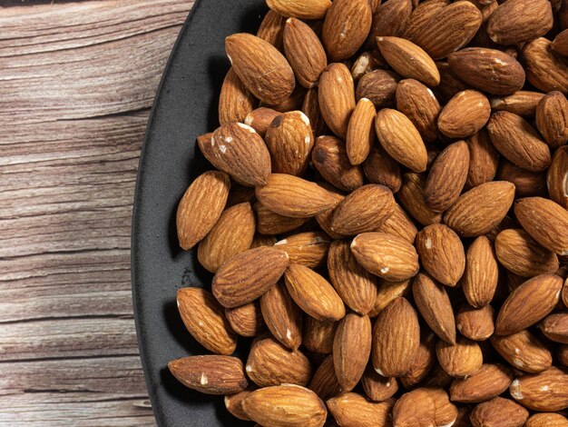 La almendra en placa negra sobre mesa de madera por concepto de alimentación y salud