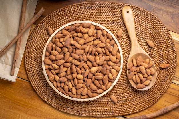 Foto almendra tostada sobre mesa de madera, almendra en plato de madera lista para servir.