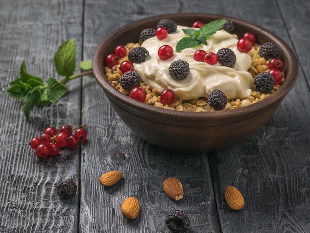 Almendras y bayas y un bol de granola y yogur sobre la mesa