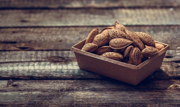 Almendras con cáscara sobre fondo de madera