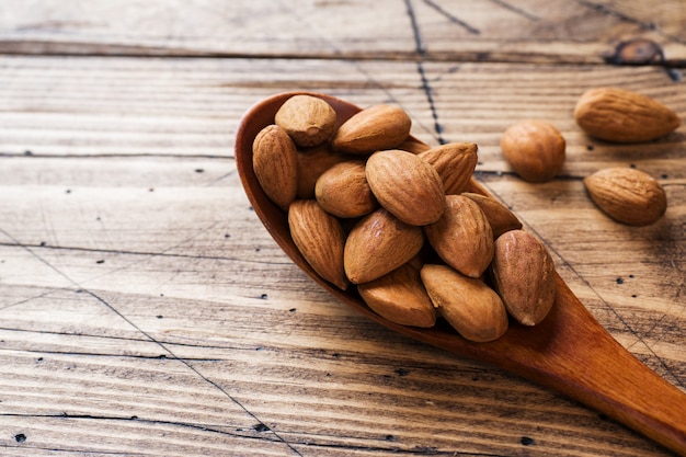 Almendras en cuchara de madera en mesa de madera