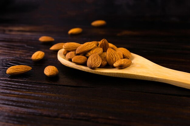 Almendras en una cuchara de madera sobre un fondo de madera oscura.