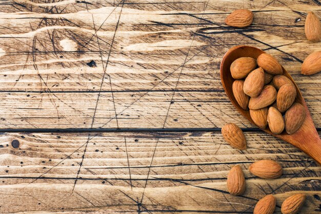 Almendras en cuchara de madera sobre fondo de madera.