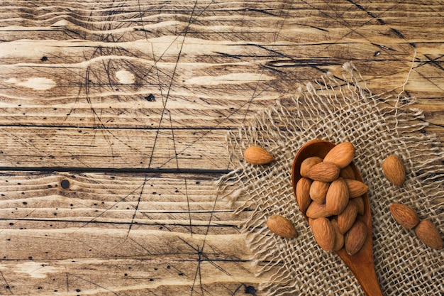 Almendras en cuchara de madera sobre fondo de madera.