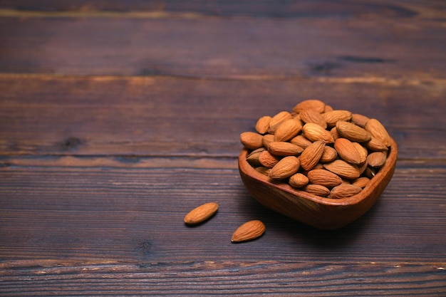 almendras en un cuenco en un espacio de copia de fondo de madera