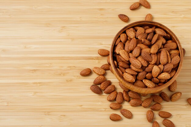 Foto almendras en cuenco de madera marrón sobre mesa de madera antigua