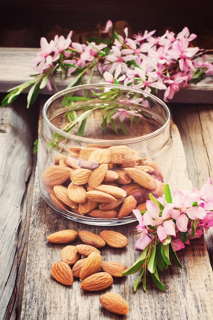 Almendras en el fondo de madera vieja, flores y nueces, teñidas