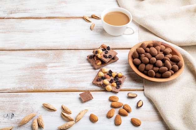 Almendras en grageas de chocolate en placa de madera y una taza de café