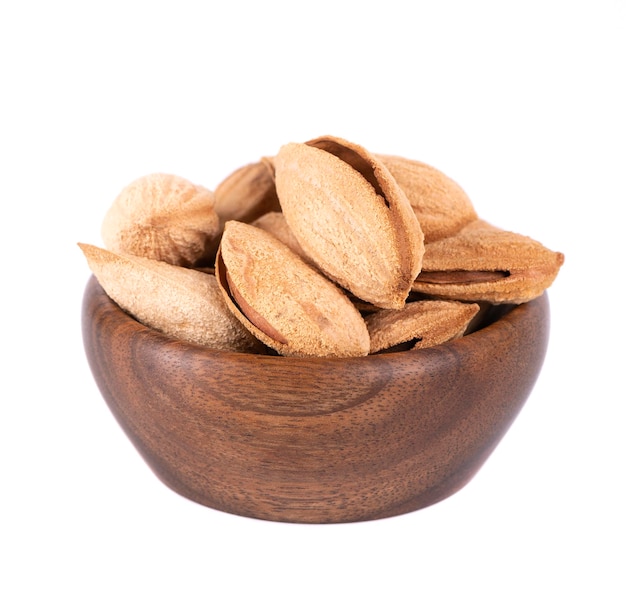 Almendras de montaña en tazón de madera aisladas sobre fondo blanco Almendras silvestres uzbekas