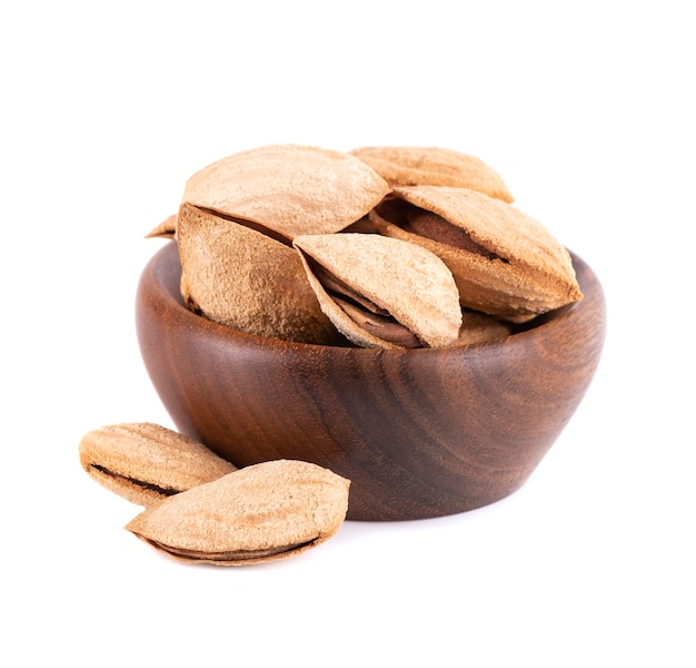 Almendras de montaña en tazón de madera aisladas sobre fondo blanco Almendras silvestres uzbekas