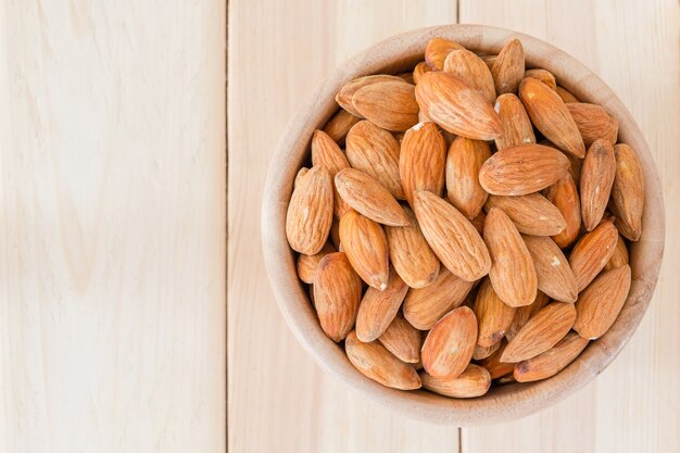 Almendras de nuez en un tazón de madera en mesa de madera