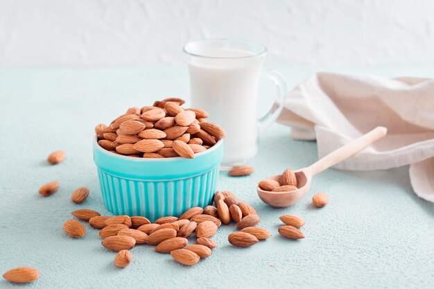 Almendras peladas en un bol y leche de almendras en un vaso sobre un fondo claro. Nutrición alternativa, fuente de vitaminas