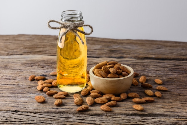 Almendras peladas con tazón y botella de aceite de almendra sobre fondo de madera rústica