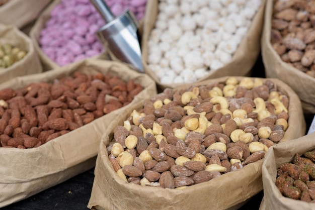 Almendras y pistachos con especias yacen en bolsas de papel en el mostrador