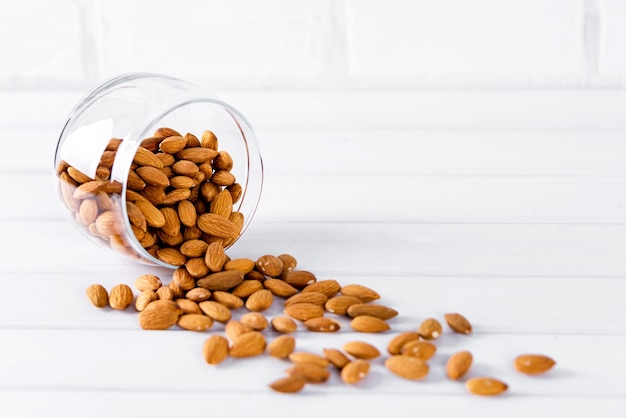 Almendras en recipiente de vidrio sobre fondo blanco.