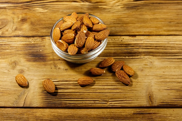 Almendras en recipiente de vidrio sobre una mesa de madera rústica