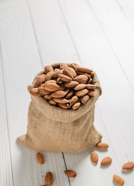 Almendras en sacos de cáñamo colocados sobre un piso de madera blanca