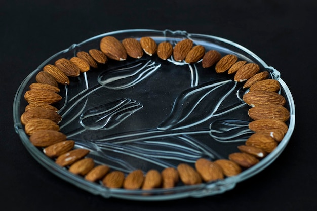 Almendras sobre un fondo negro negro en placa de vidrio Nueces Almendra en un vaso