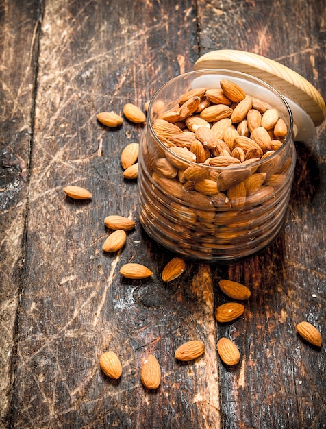 Almendras en tarro sobre mesa de madera.