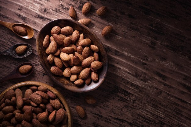 Almendras en una taza de madera y cuchara con espacio de copia