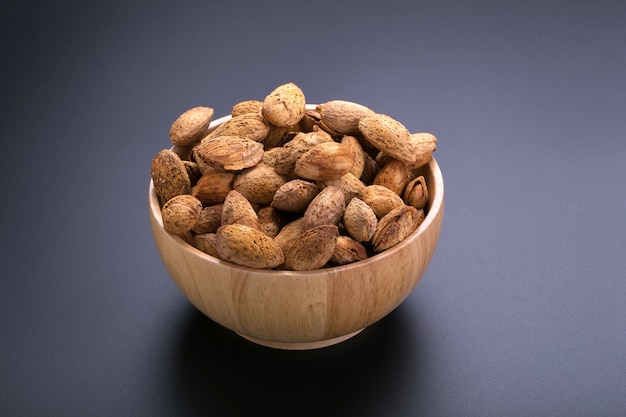 Almendras en un tazón de madera sobre un fondo negro