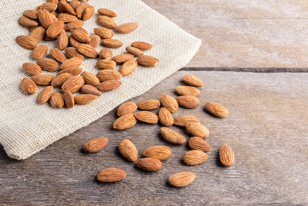 Foto almendras vierten de cuchara de madera sobre fondo de madera