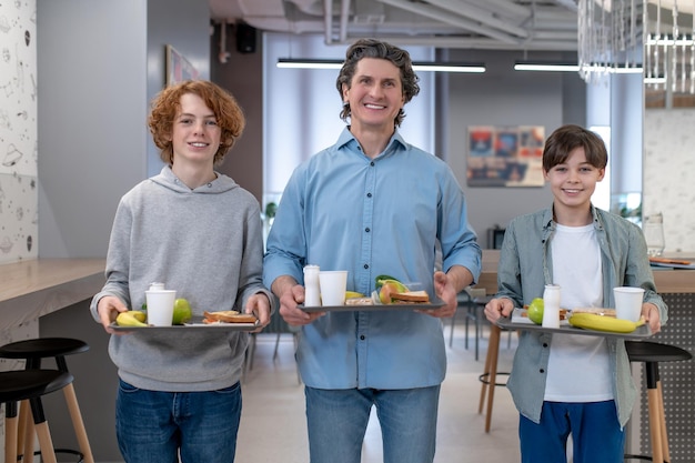 Almoçar juntos. Meninos da escola e seu professor almoçando juntos na cantina da escola