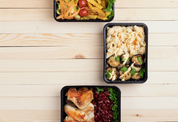 Foto almoço de negócios em caixas de comida, asas de frango assado, legumes cozidos no vapor, carne cozida, refeição pronta para comer