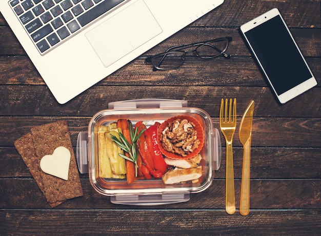 Almoço de negócios saudável no local de trabalho Legumes grelhados e lancheira de frango frito na mesa de trabalho