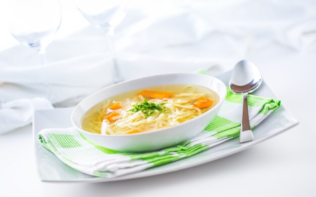 Almoço pondo mesa com frango ou sopa de carne com macarrão, cenoura e ervas.