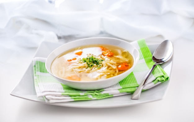 Almoço pondo mesa com frango ou sopa de carne com macarrão, cenoura e ervas.