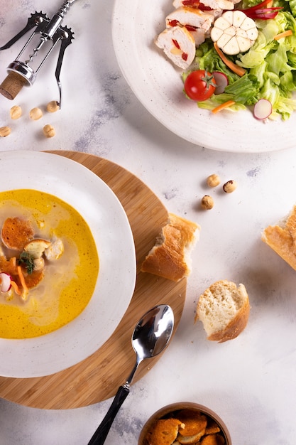 Almoço sopa de frango com croutons e salada de peito de frango e vinho sobre um fundo claro