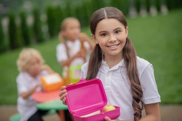 Almoço. uma menina com uma lancheira sorrindo bem