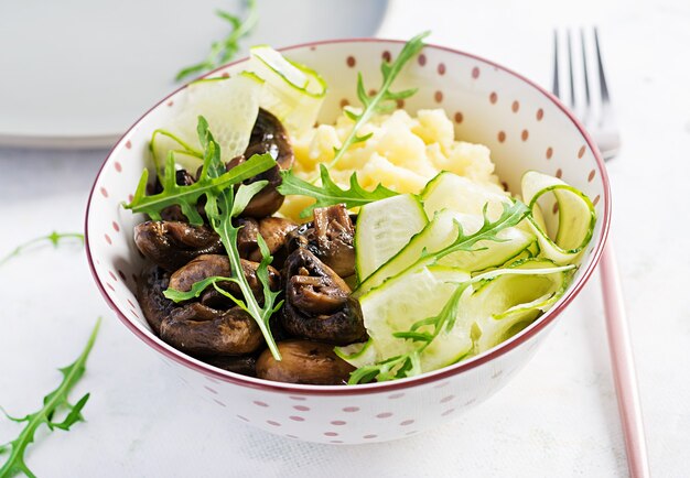 Almoço vegano saudável com purê de batata e cogumelos assados com pepino fresco