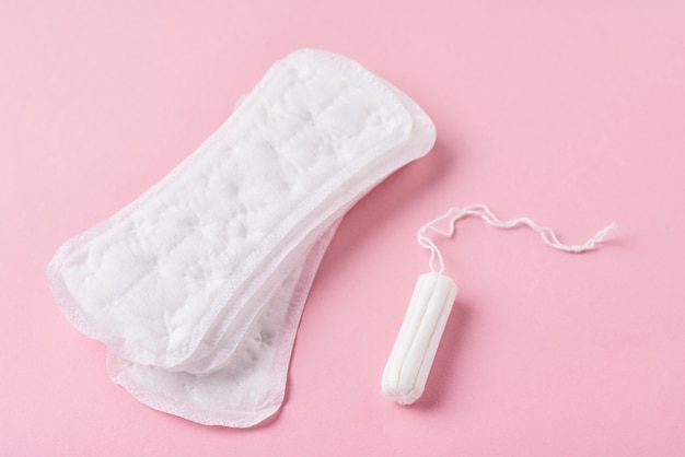 Almofada sanitária e tampão menstrual em um fundo rosa