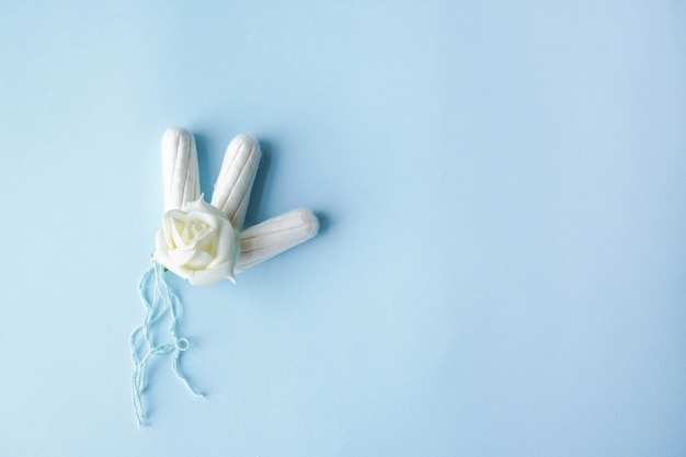 Almofadas de algodão menstrual de tampão no espaço azul cópia com flor branca