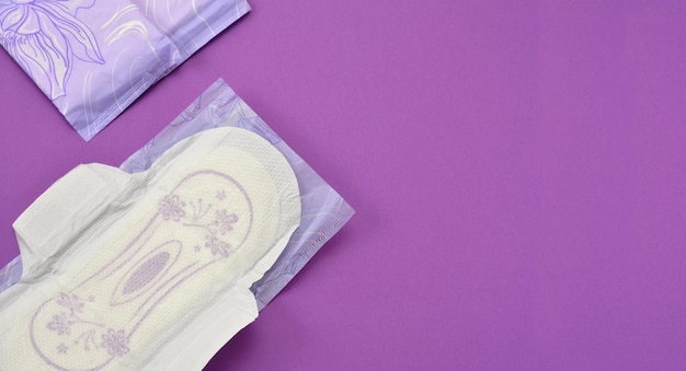 Almofadas de produtos de higiene feminina em um banner de espaço de cópia de fundo roxo