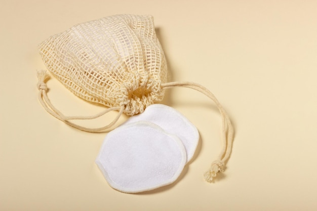 Almofadas de remoção de maquiagem reutilizáveis de algodão em uma bolsa de pano em fundo bege O conceito de ecologia e consumo consciente Almofadas de algodão reutilizáveis