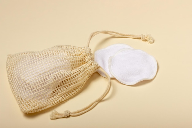 Almofadas de remoção de maquiagem reutilizáveis de algodão em uma bolsa de pano em fundo bege O conceito de ecologia e consumo consciente Almofadas de algodão reutilizáveis