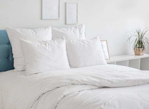 Almofadas e edredons brancos na cama azul.