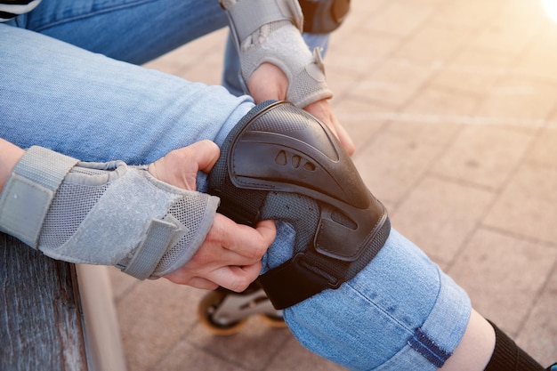 Almofadas e joelheiras patinadora de mulher colocando joelheiras na perna equipamento de segurança para patinadora acessórios de segurança para patinar