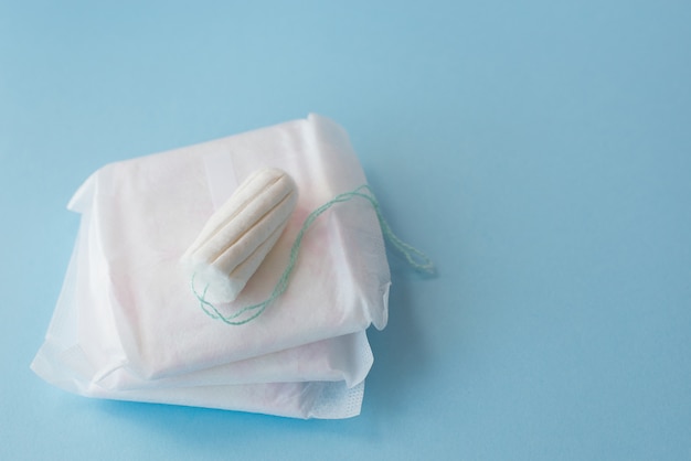 Almofadas menstruais, tampão em um fundo azul