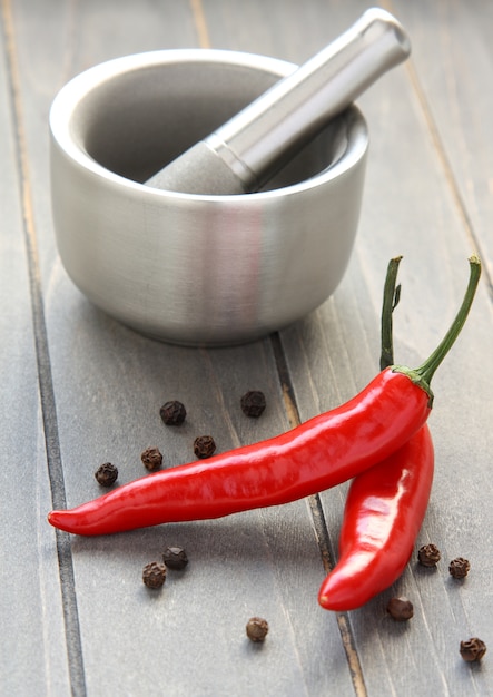 Almofariz e pilão de metal com pimenta em fundo de madeira