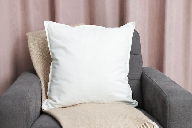 Almohada suave en blanco en el sillón acogedor en casa